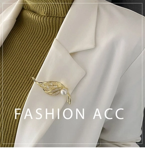 Detail of a golden leaf brooch with pearls and zircon pinned on a white blazer lapel