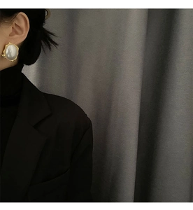 Detail of baroque pearl earring with irregular gold wavy base worn by a model