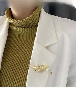 Detail of leaf-shaped pearl brooch with shimmering zircons on a white blazer
