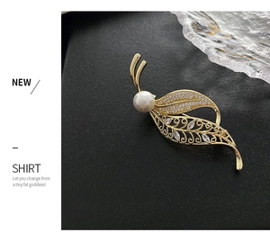 Detailed view of leaf brooch with pearls and crystals on a black stand