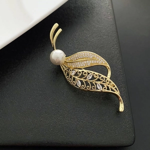 Elegant gold leaf brooch featuring white pearls and sparkling cubic zirconia stones