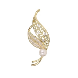 Elegant gold leaf brooch with white pearl and sparkling crystals on a clean white background