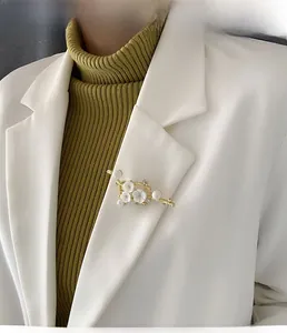 Floral shell brooch with pearls and rhinestones on a white blazer lapel detail