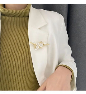 Detail of flower brooch with white shells and pearls on a white blazer lapel