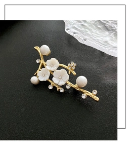 Close-up of elegant floral branch brooch with shell flowers and delicate white pearls