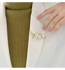 Floral shell brooch with pearls pinned on a white blazer lapel for elegant styling