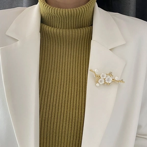 Elegant gold plum blossom branch brooch with white shell petals and pearls on a white suit