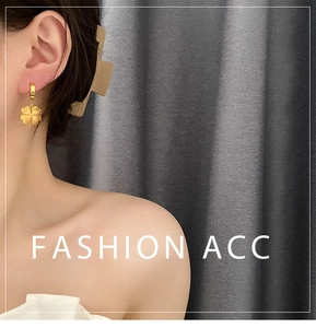 Detailed view of a gold clover charm earring with a textured finish on a model