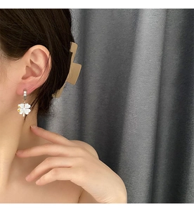 Detail of four-leaf clover drop earrings with white finish and silver steel hoop