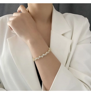 Gros plan d'un bracelet doré orné de zircons élégants porté par une femme en blanc