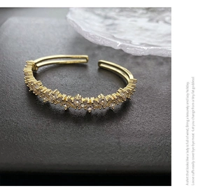 Gros plan sur un bracelet jonc doré avec pavage de zircons sur fond de pierre grise