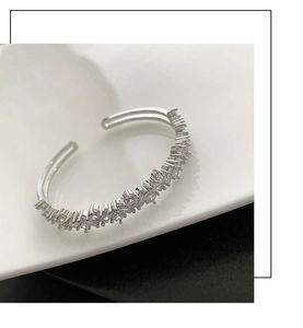 Gros plan détaillé d'un bracelet ouvert argenté serti de zircons sur une assiette blanche