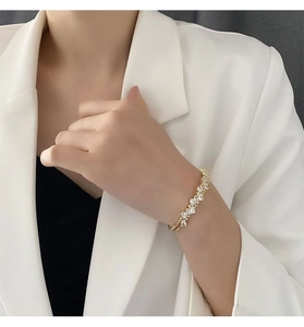 Vue détaillée d'un bracelet doré à double couche avec zircons sur un poignet