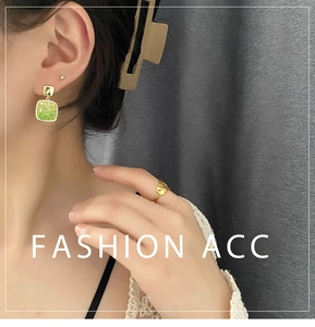 Detail shot of green square earrings and gold hollow ring on model for fashion display