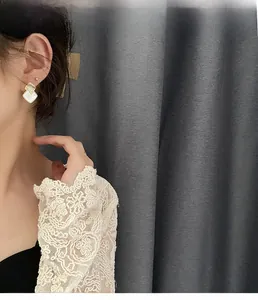 Detail of square white mother-of-pearl stud earrings with gold plating on female model