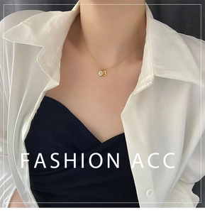 Detail of a gold titanium steel necklace with a letter B pendant and a small round disc