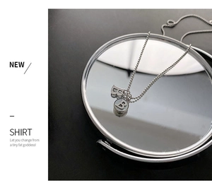Macro view of silver letter B double pendant necklace on a round mirror reflective surface