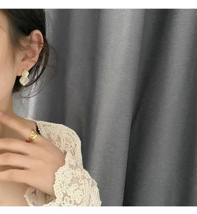 Detail of gold geometric earrings with white inlay and wide hollow open ring set