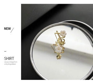 Detailed close-up of gold flower stud earrings with cream petals and zircon accents