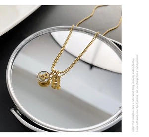 Detailed shot of golden letter B pendant with pearl inlay on a reflective mirror base