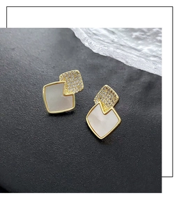 Macro shot of geometric gold studs featuring pave crystals and white opal stones