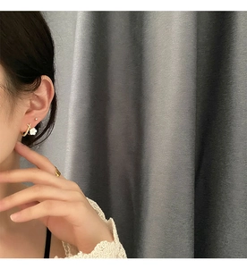 Detail shot of a white floral earring with gold clasp worn by a female model
