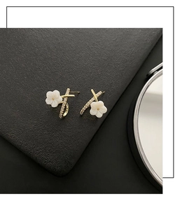 Close-up of elegant gold flower earrings with white petals and shimmering micro-diamonds