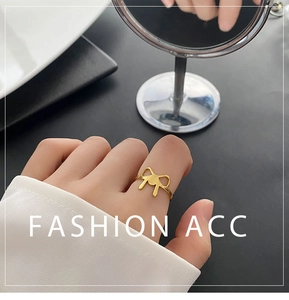 Detailed view of a gold bow ring on a finger, featuring a sleek and minimalist design