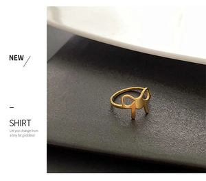 Macro shot of minimalist gold bow ring in titanium steel on a high-contrast background