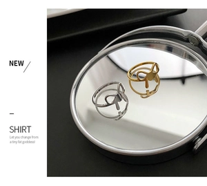 Detail view of gold and silver minimalist geometric hollow rings on a reflective mirror surface
