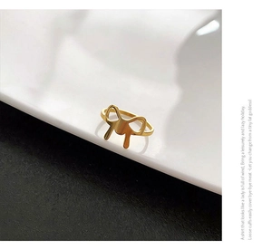 Macro detail of golden bow-shaped titanium steel ring on minimalist porcelain