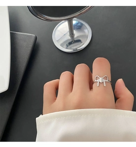 Close-up of polished silver titanium steel ring with a hollow bow design on index finger
