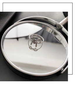 Macro view of a bow-knot silver steel ring reflecting on a round cosmetic mirror