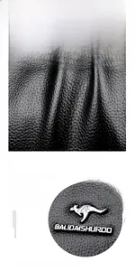 Dettaglio texture pelle cerata nera e logo a canguro argentato sulla borsa donna