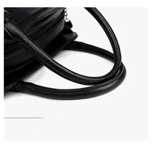 Dettaglio dei manici in pelle con grana litchi su una borsa a spalla nera minimal