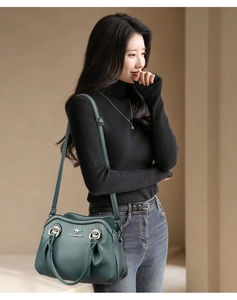 Borsa tote in pelle martellata verde scuro indossata a spalla da una modella