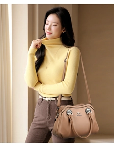 Dettaglio borsa tote in pelle marrone con stemma d'argento e manici ad anello in metallo