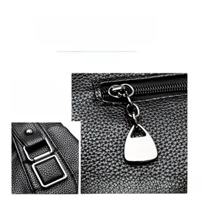 Close-up of litchi leather texture with silver hardware and adjustable buckles on tote bag