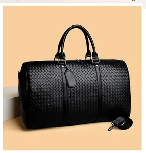 Detailaufnahme der schwarzen Reisetasche aus geflochtenem Leder mit verstärkten Griffen