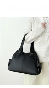 Detail view of large black tote bag with litchi grain texture and side zipper pocket