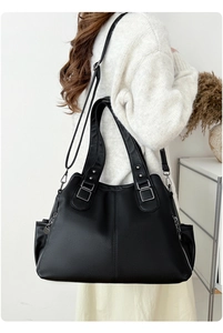 Detail of large black lychee leather tote bag featuring side zippers and adjustable strap