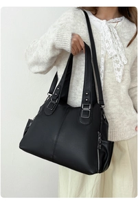 Detail view of large black lychee pattern leather tote bag shown on a female model