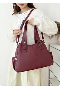 Detail of burgundy pebbled leather tote bag featuring multiple zippers and gunmetal hardware