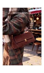 Borsa a tracolla in pelle scamosciata marrone con fibbia dorata in un ambiente da caffè