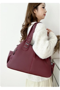 Detail of burgundy pebbled leather tote bag with side zipper pocket and metal hardware