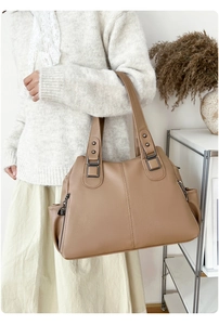 Detail view of khaki pebbled leather tote with bronze hardware and side zipper pockets