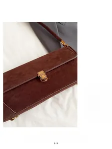 Dettaglio della borsa baguette in pelle scamosciata marrone con chiusura dorata