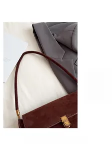 Dettaglio macro di borsa baguette in camoscio marrone con elegante fibbia in metallo dorato