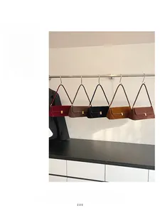 Borse baguette in camoscio in cinque colori appese a un supporto in metallo