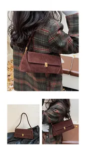 Dettaglio borsa baguette in camoscio marrone con chiusura girevole dorata e finitura opaca